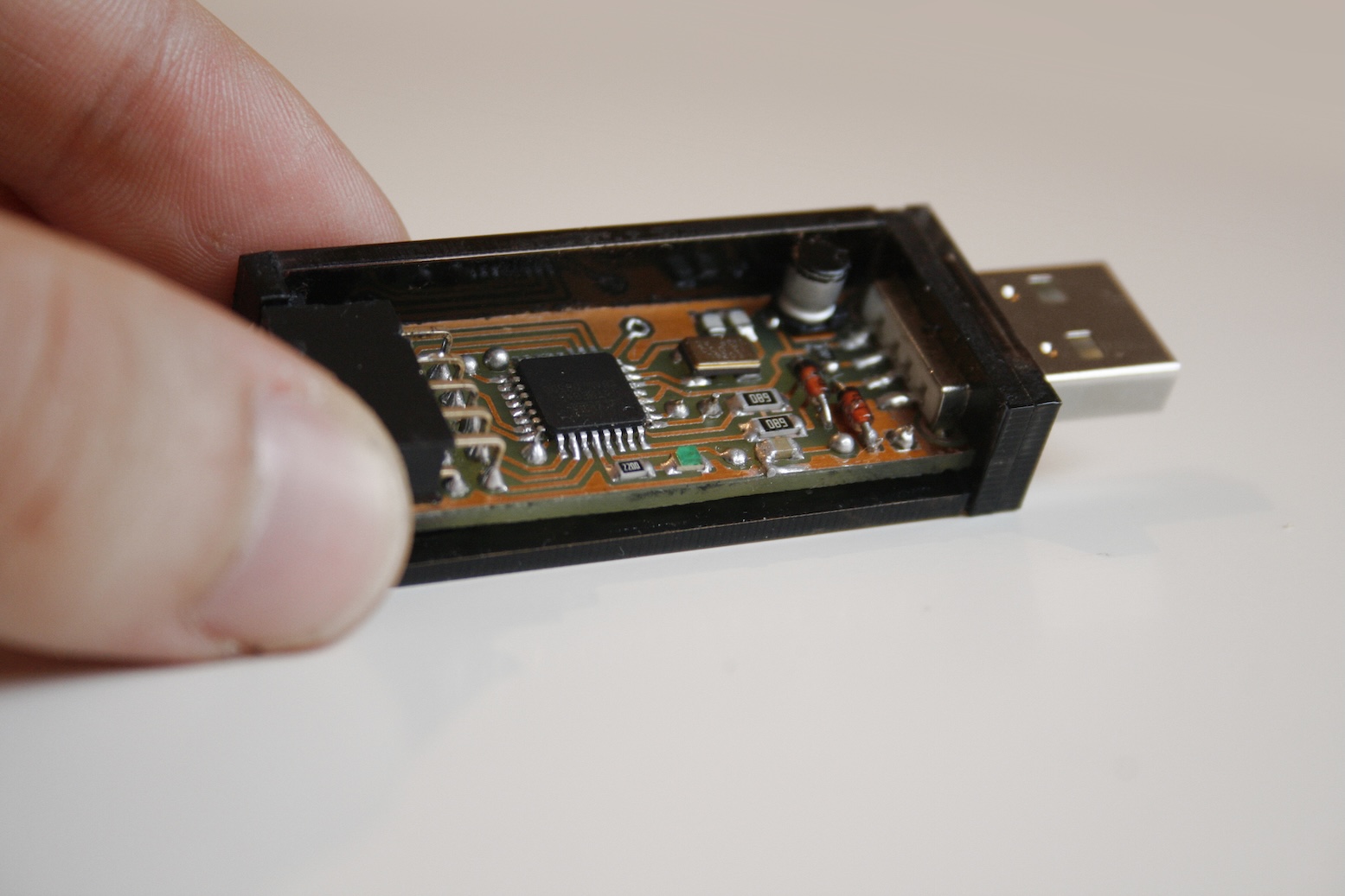 A printed circuit board with smd-components and a microcontroller hold by fingers