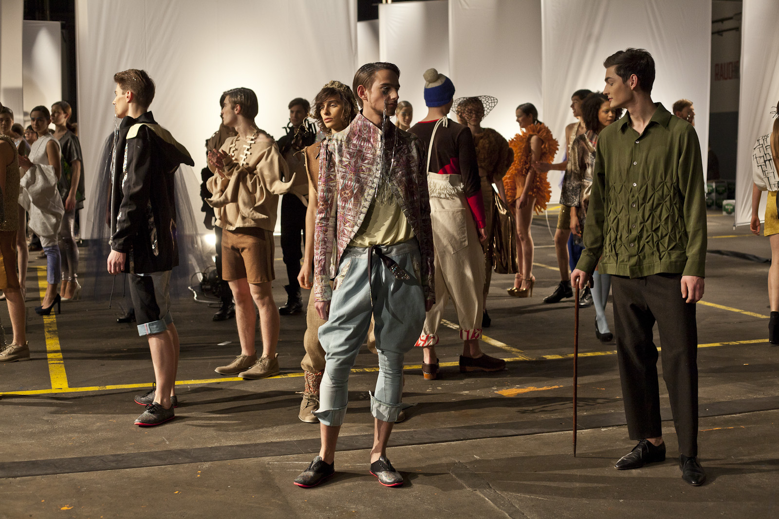 Fashion models standing in an industrial hall with white sails in the background